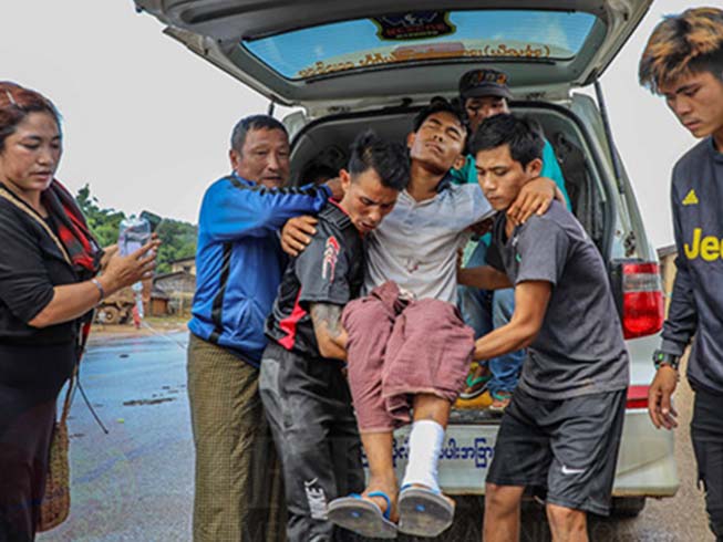 A Christian who was shot in the leg when the Myanmar army carried out an attack on a majority-Christian area, is helped from a car on his way to hospital
