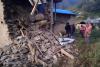 A group of people standing next to a pile of rubble from a ruined house after the recent earthquake in Nepal