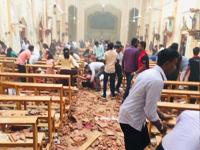 Worshippers move about a Sri Lankan church in the aftermath of one of the deadly explosions that targeted Christians in Sri Lanka on Easter Sunday